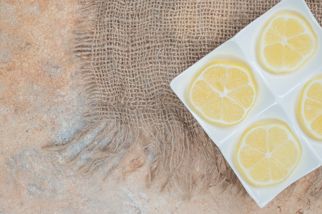 Assiette de tranches de citron frais sur toile de jute.