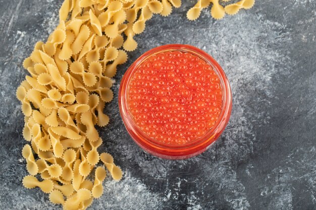 Photo gratuite une assiette en verre de caviar d'esturgeon rouge avec des pâtes non cuites .