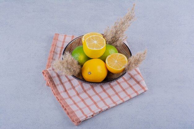 Assiette en verre de citrons juteux frais sur pierre.