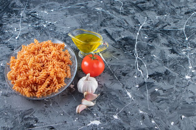 Assiette en verre de délicieuses pâtes fusilli et légumes sur fond de marbre.