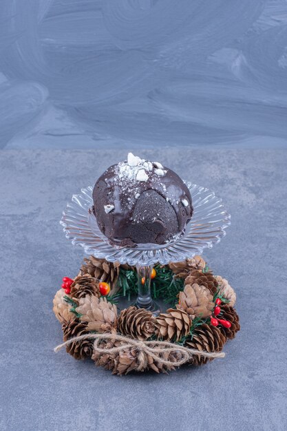 Photo gratuite une assiette en verre avec un gâteau au chocolat et des pommes de pin
