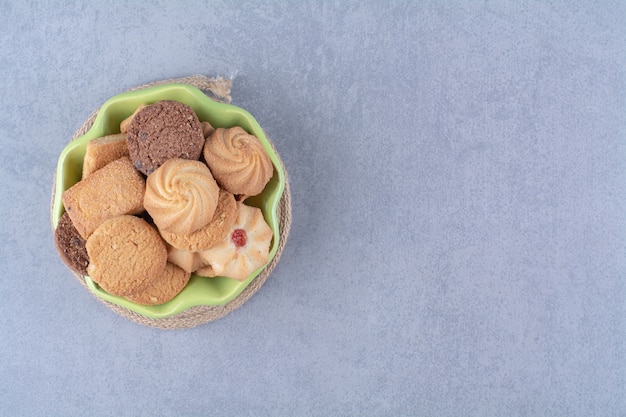 Une assiette verte avec de délicieux biscuits ronds doux sur un sac.