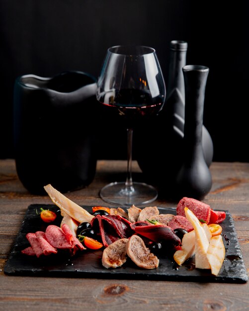 Assiette de viande aux olives et tomates servie avec un verre de vin