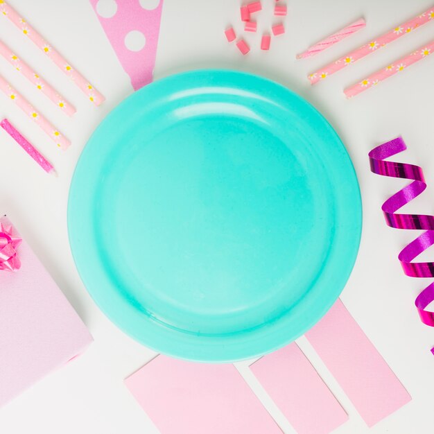 Assiette vide turquoise avec des objets décoratifs sur fond blanc