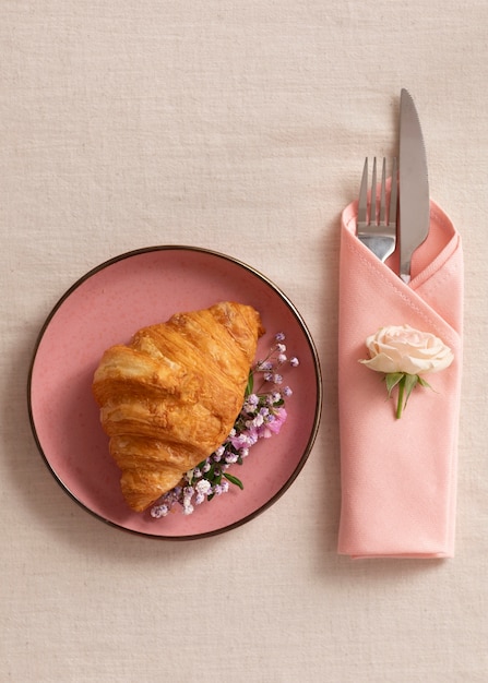 Photo gratuite assiette vue de dessus avec croissant et fleurs