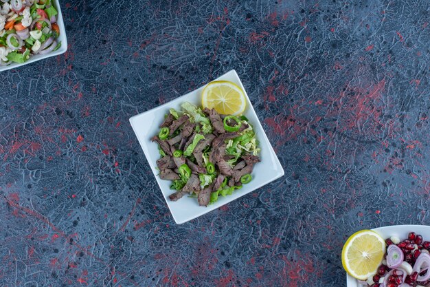 Assiettes blanches de salades de viande et de légumes.