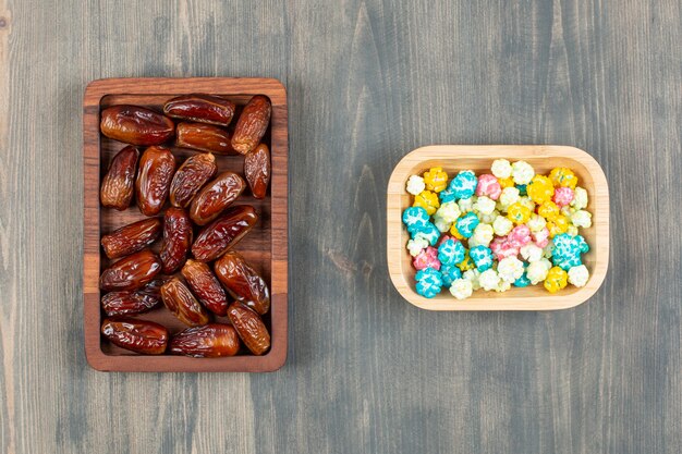 Assiettes de dattes et pop-corns colorés sur une surface en bois