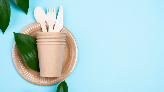 Assiettes jetables avec tasses et couverts fond bleu espace copie