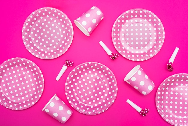 Photo gratuite assiettes en pointillés et sifflets et tasses sur fond rose