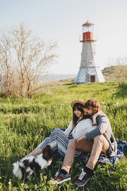 Assis dans l'herbe, jeune couple hipster élégant amoureux de chien dans la campagne