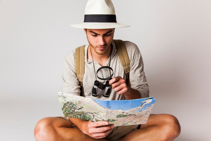 Photo gratuit assis touriste regardant la carte avec une loupe