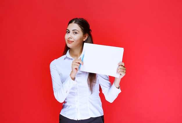 Assistant en chemise blanche tenant et démontrant des rapports et des corrections sur eux.