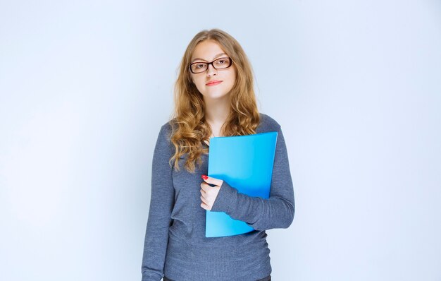 Assistant avec des lunettes tenant un dossier de rapport bleu.