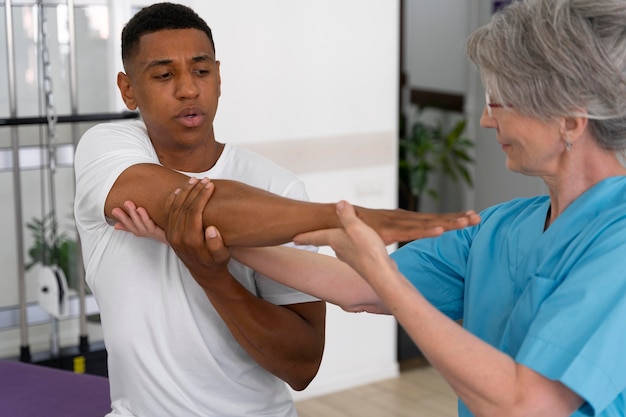 Photo gratuite assistant médical aidant le patient avec des exercices de physiothérapie