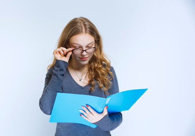 Assistant ouvrant le dossier de rapport bleu et le vérifiant.