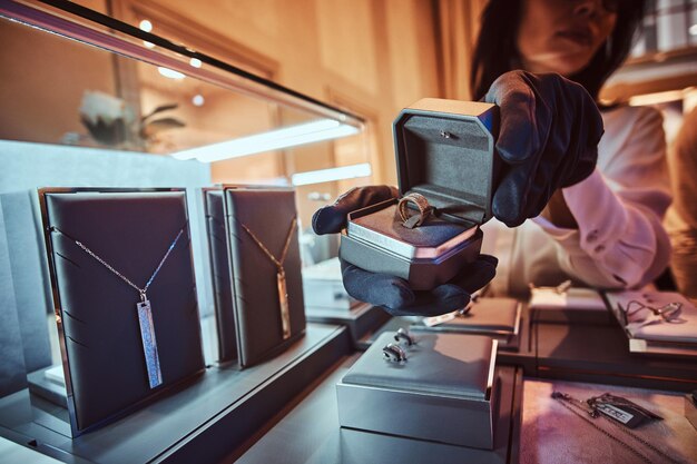 Une assistante montre la bague en or exclusive dans la bijouterie de luxe
