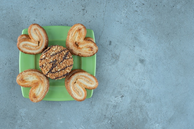 Assortiment de biscuits sur un plateau vert sur une surface en marbre