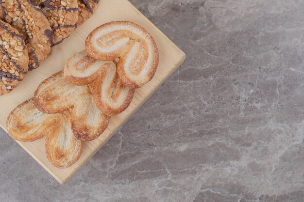 Assortiment de collations avec différents biscuits sur une petite planche sur marbre