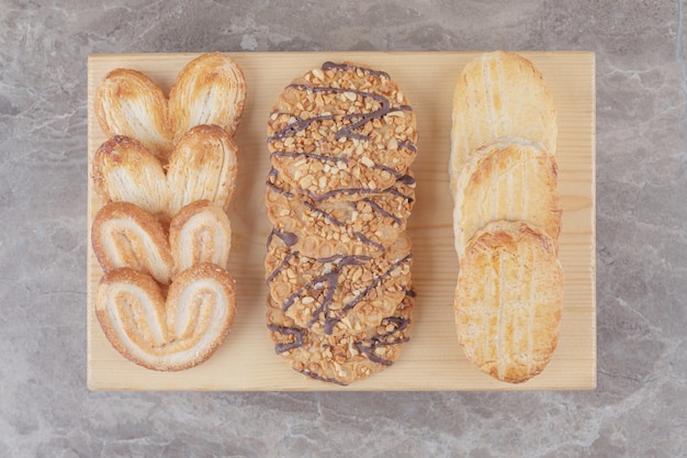 Assortiment de collations avec différents biscuits sur une petite planche sur marbre