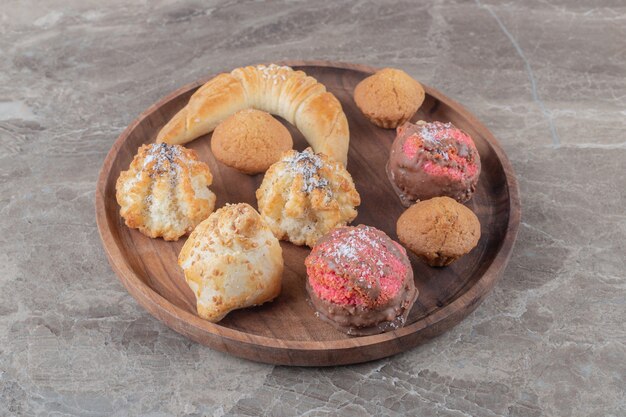 Assortiment de divers biscuits sur un plateau en bois sur une surface en marbre