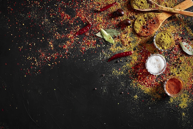 Assortiment d'épices sur fond noir foncé. Assaisonnements pour la nourriture. Curry, paprika, poivre, cardamome, curcuma. Vue de dessus. Fermer. Notion d'épices. Ingrédients d'épices pour cuisiner