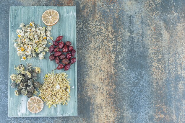 Assortiment de fleurs séchées et d'églantier sur planche de bois.