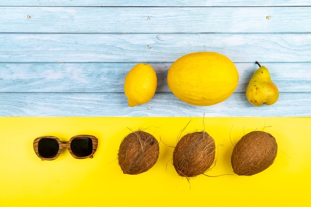 Un assortiment de fruits jaunes et de verres se trouve sur un fond en bois bleu et un fond jaune