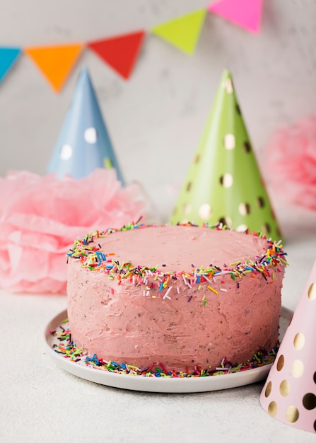 Assortiment avec gâteau rose et chapeaux de fête