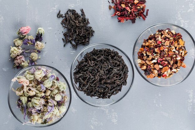 Assortiment d'herbes séchées dans des bols en verre sur une surface en plâtre