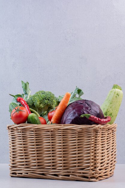 Assortiment de légumes biologiques dans un panier en bois.