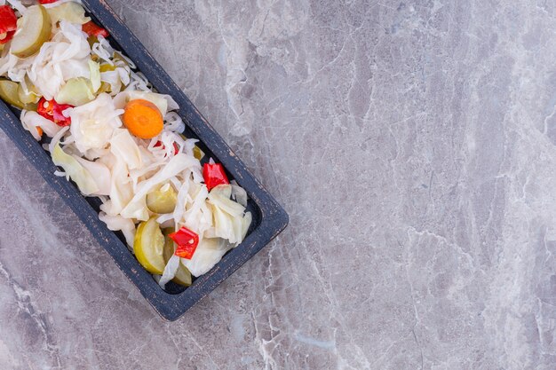 Assortiment de légumes marinés sur une planche, sur le marbre.