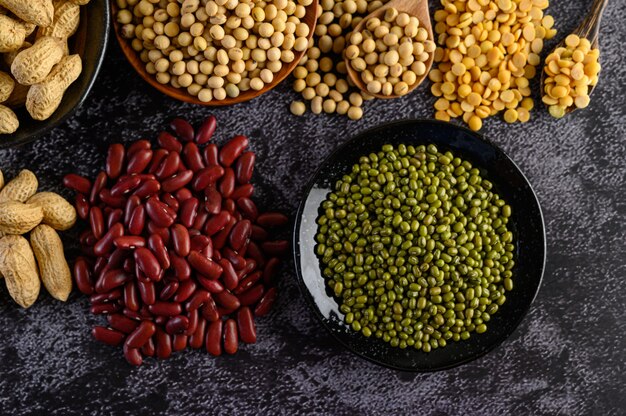 Assortiment de légumineuses et de haricots sur le sol en ciment noir.