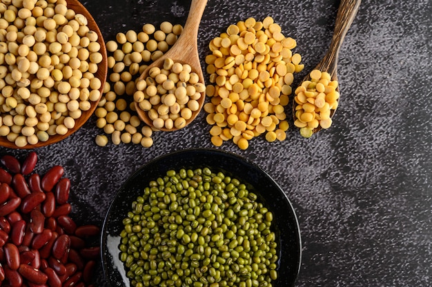 Assortiment de légumineuses et de haricots sur le sol en ciment noir.