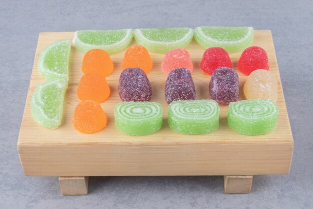 Assortiment de marmelades sur une planche de bois sur une table en marbre.