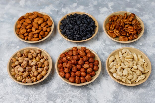 Assortiment de noix dans des assiettes en céramique. Noix de cajou, noisettes, noix, pistache, pacanes, pignons de pin, cacahuètes, raisins secs.