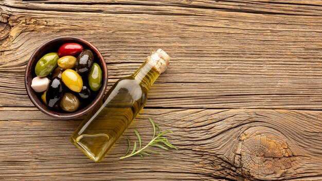 Photo gratuite assortiment d'olives colorées avec bouteille d'huile et espace de copie