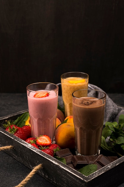 Assortiment de verres à milk-shake sur plateau avec chocolat et fruits