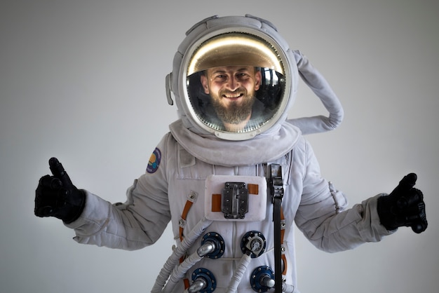 Photo gratuite astronaute masculin entièrement équipé souriant et montrant les pouces vers le haut