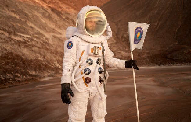 Astronaute masculin tenant un drapeau coincé dans le sol sur une planète inconnue