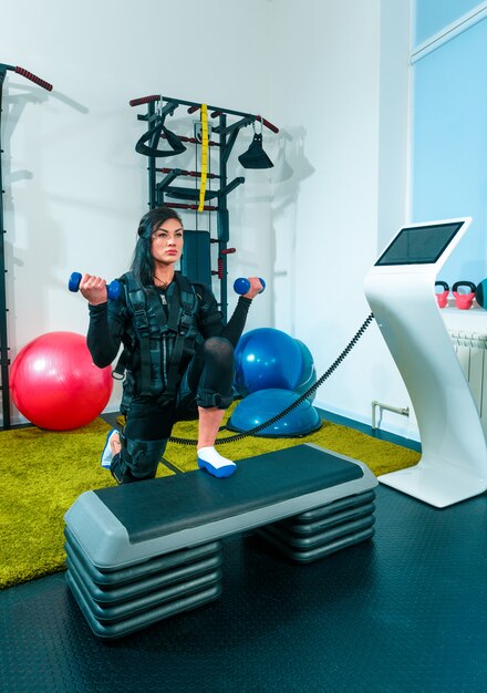 L'athlète féminine faisant de l'exercice dans un studio de remise en forme ems