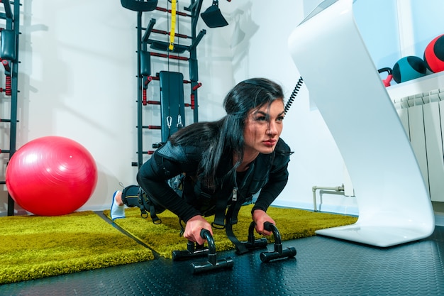 Photo gratuite l'athlète féminine faisant ils exercent dans un studio de remise en forme ems