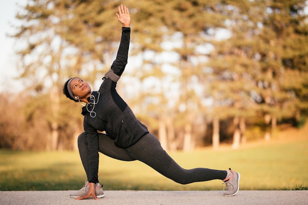 Photo gratuite athlète féminine noire s'échauffant avant l'entraînement des ports et faisant des exercices d'étirement dans le parc