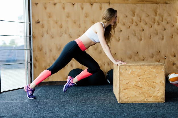 Athlète féminine pratiquant des pompes et des burpees dans une salle de sport