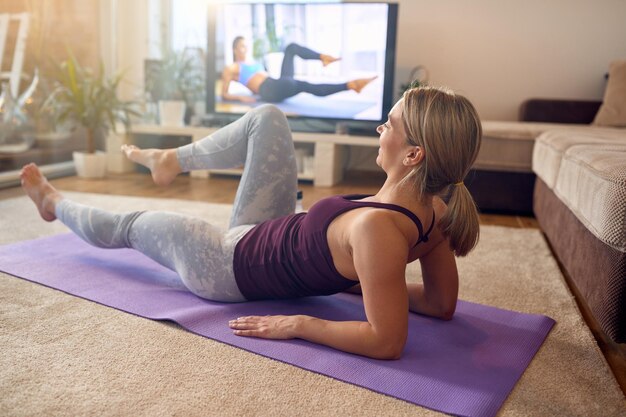 Athlète féminine pratiquant ses abdominaux inférieurs pendant l'entraînement à domicile