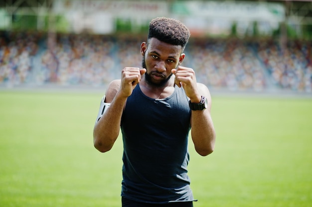 Athlète masculin afro-américain boxeur homme en vêtements de sport faisant des étirements au stade