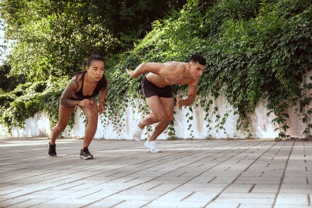 Un athlète musclé faisant de l'exercice au parc. Gymnastique, entraînement, flexibilité des entraînements de fitness. Ville d'été en journée ensoleillée sur le terrain de fond. Mode de vie actif et sain, jeunesse, musculation.