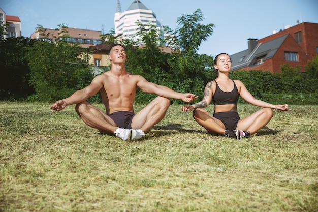 Un athlète musclé faisant de l'exercice au parc. Gymnastique, entraînement, flexibilité des entraînements de fitness.