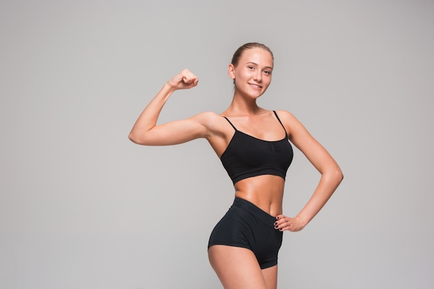 Athlète musclé de jeune femme sur fond gris