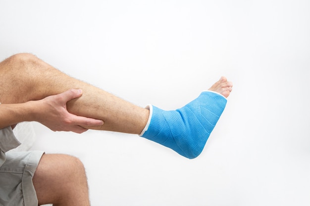 Attelle de cheville bleue. Jambe bandée moulée sur patient de sexe masculin sur fond blanc isolé. Concept de blessure sportive.