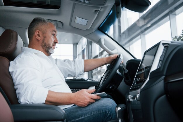 En attente d'un appel. Homme d'affaires est assis dans la voiture moderne et a des offres